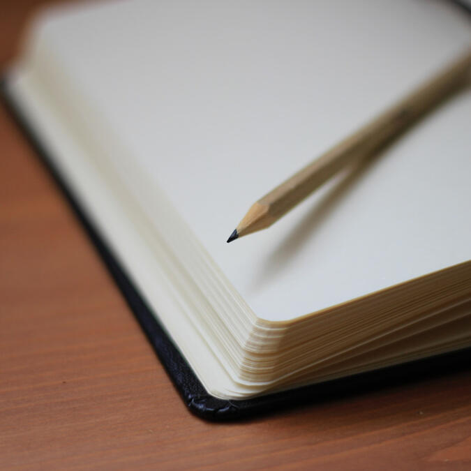 Blank journal sits on table with sharpened pencil