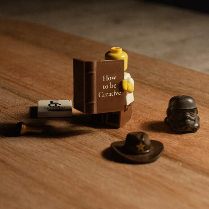 Little lego man reads tiny book entitled "How to be Creative"